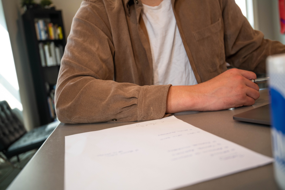 Person working through printed paperwork at a desk