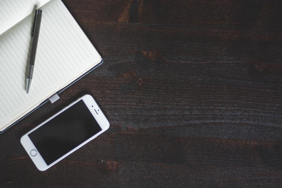 Phone and notebook on a dark wooden desk