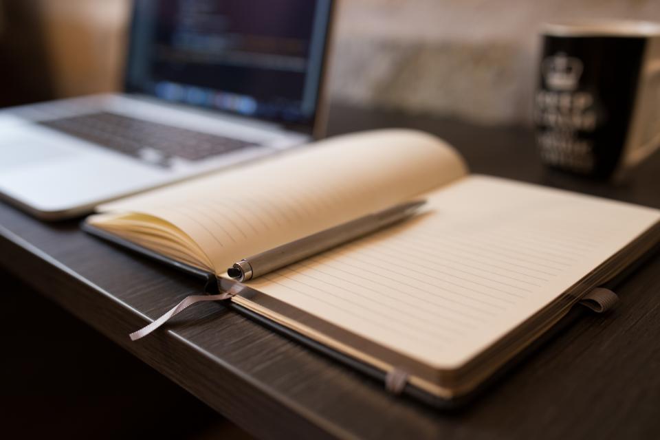 Open booklet beside a laptop on a desk